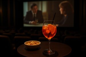 Tavolino con bicchiere di spritz e noccioline all'interno di una sala del cinema