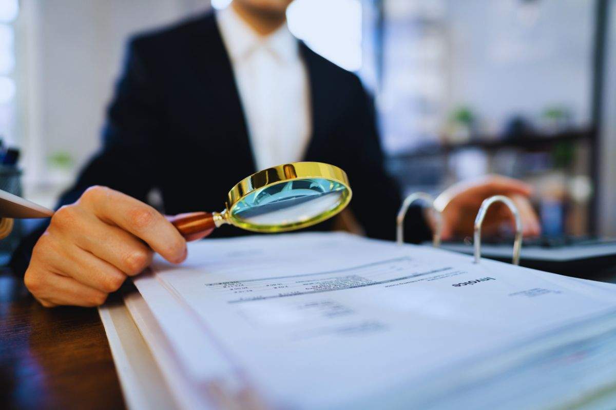 Impiegato che controlla documento con una lente d'ingrandimento