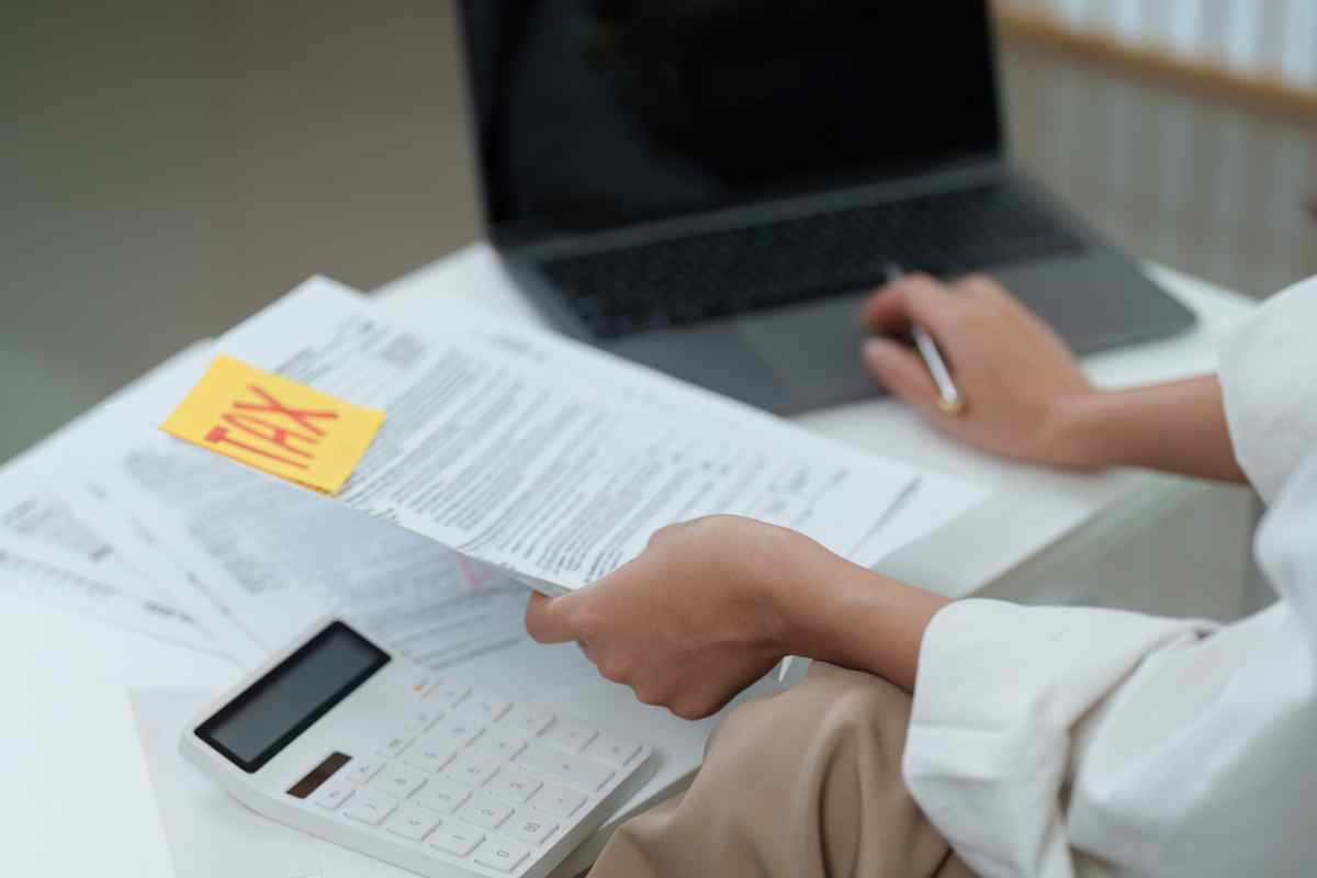 Documenti fiscali con scritta Tax, calcolatrice e pc portatile