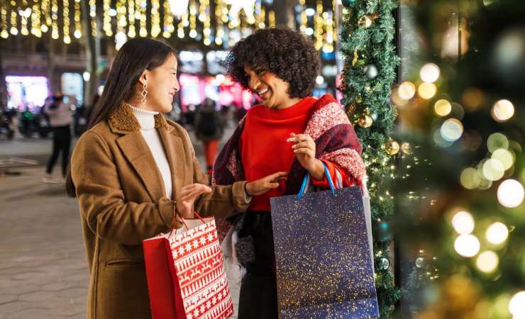 Due donne che camminano con decorazioni di Natale attorno